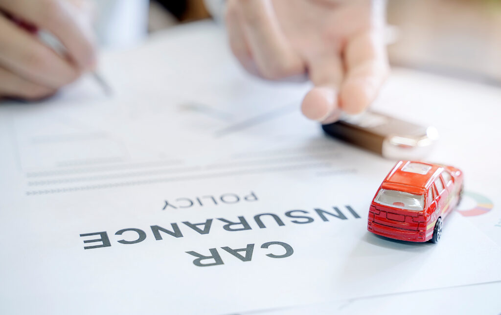 Car insurance policy with red car toy and blur image of man hand